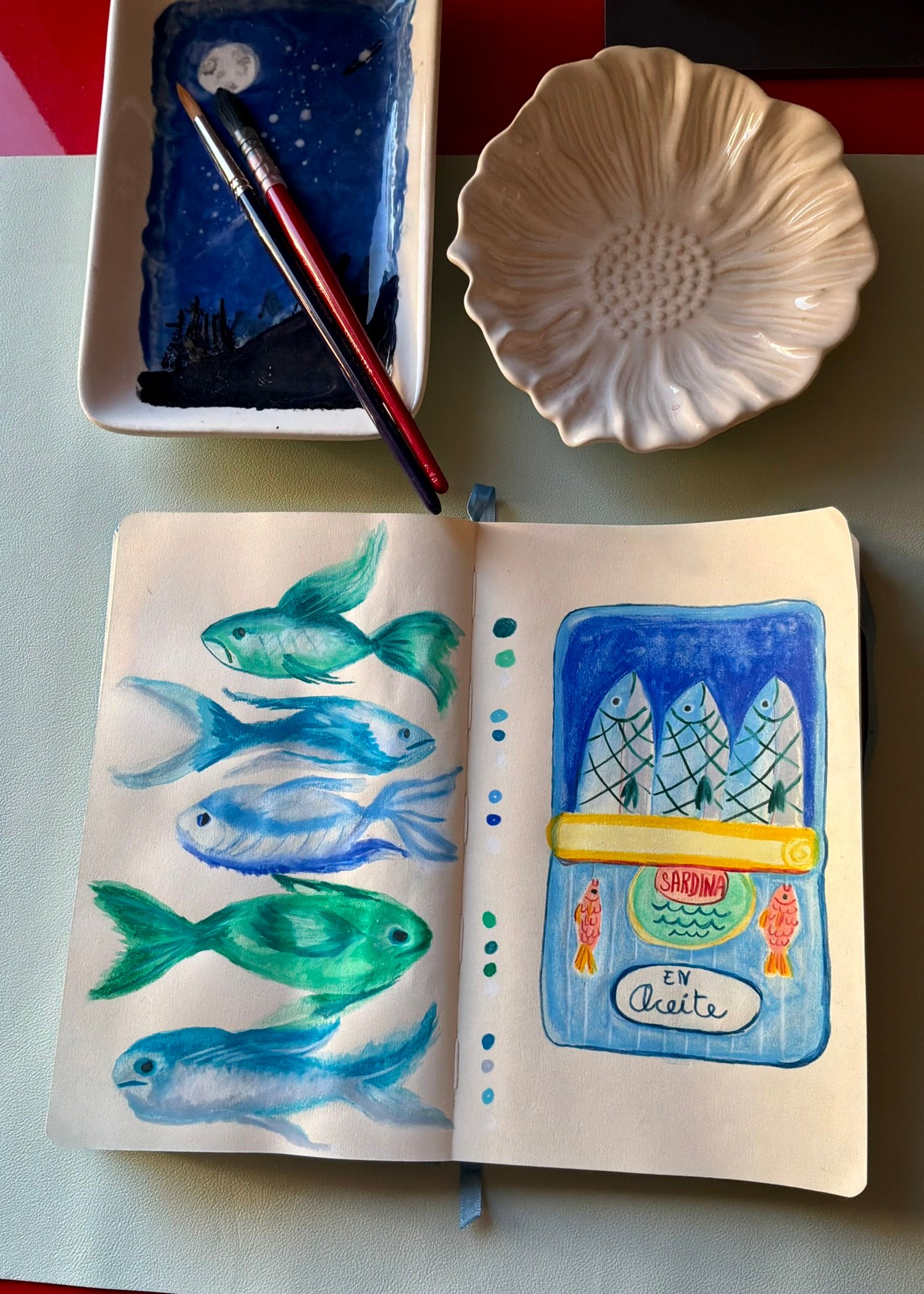 cuaderno abierto con dibujo de pececillos azules pintados en acuarela